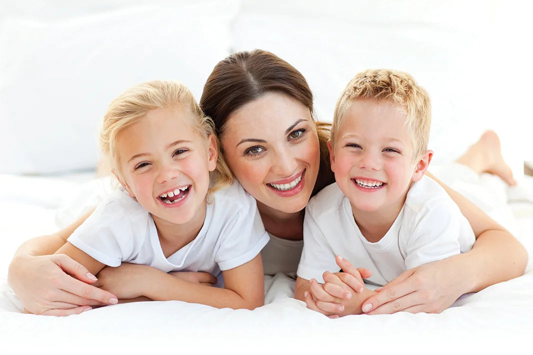 mother holds son and daughter in bed