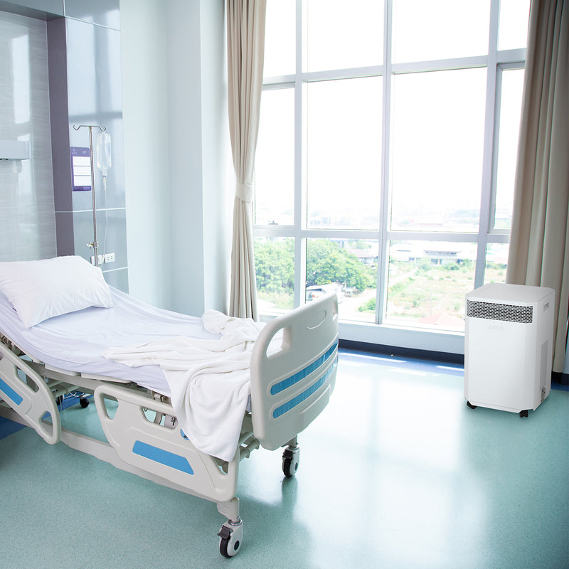 Load image into Gallery viewer, A hospital ward with single unoccupied bed. An INOVA air purifier is sitting near a window, quietly cleaning the air, removing harmful viruses, keeping the staff and patients safe from the risk of infection.