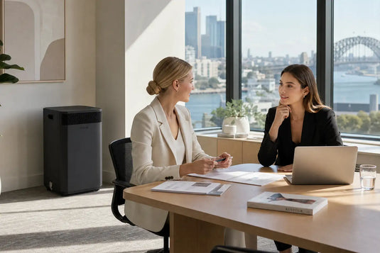 Two women meeting in a Sydney Office with a Black INOVA E20 Air Purifier in the background