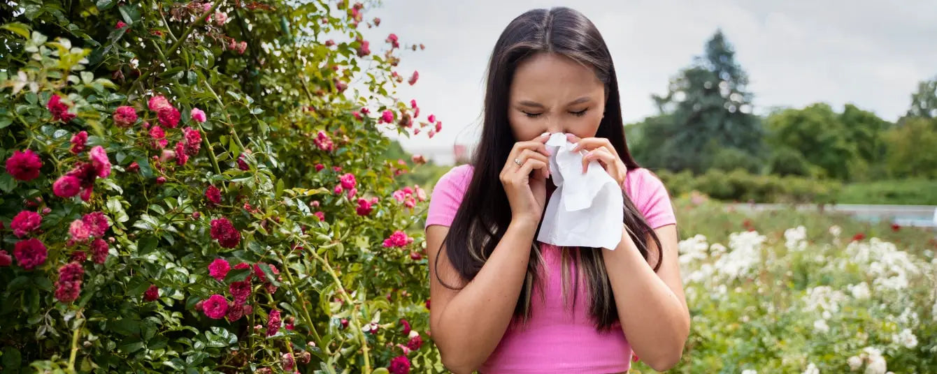 young girl sneezes near flowers
