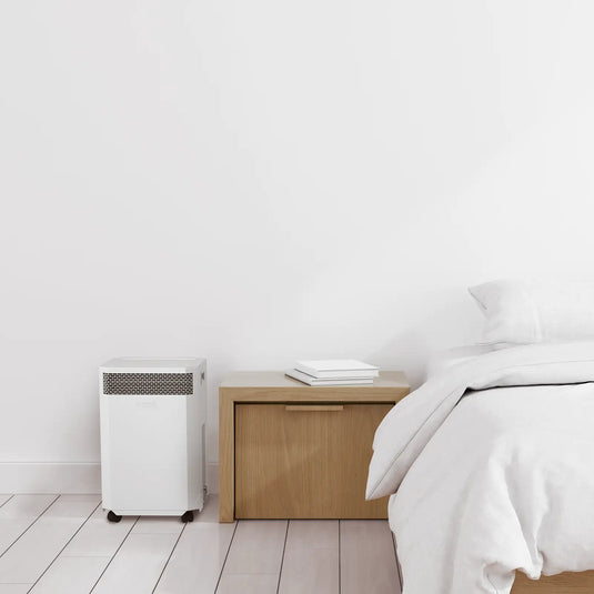 white inova air purifier next to bed